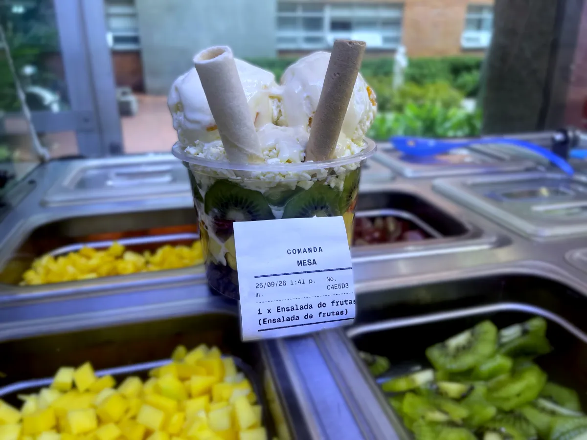 Ensalada de frutas con helado y la comanda impresa desde Dayvent pegada al vaso, sobre la barra de frutas.